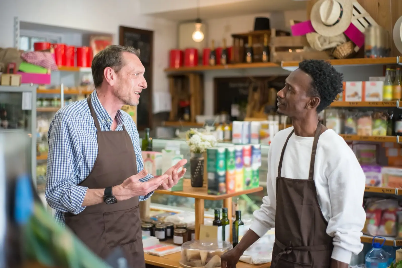 Two staff in aprons talking in a deli